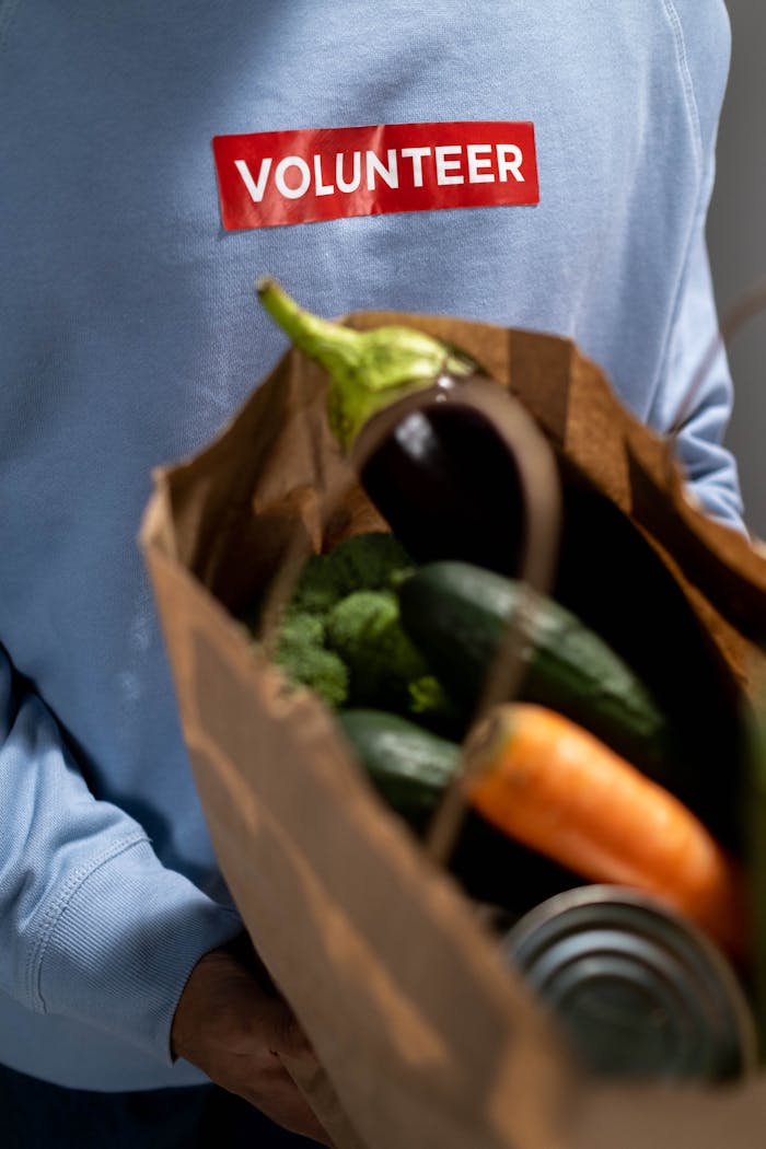 our-story A volunteer holds a paper bag filled with fresh vegetables, symbolizing community service and support.